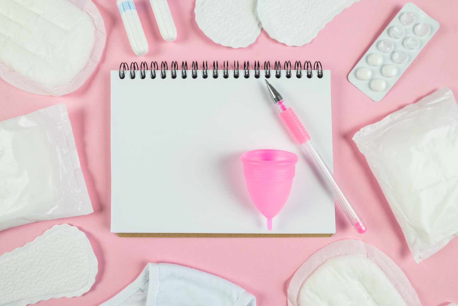 top view photo open planner sanitary napkins tampons underwear pills isolated pastel pink background with blank space scaled